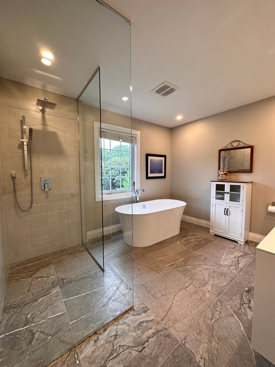 Grande salle de bain avec douche vitrée et bain, planchers et murs en céramique