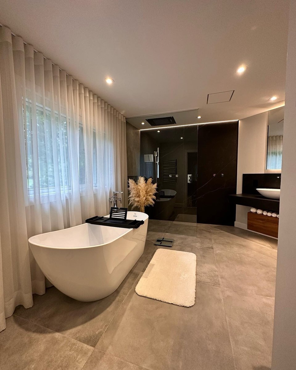 Grande salle de bain avec douche vitrée, plancher et murs en céramique